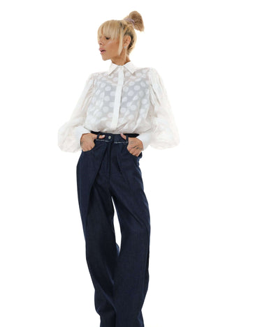 Model wearing a white sheer polka dot shirt with puff sleeves paired with navy wide-leg trousers.