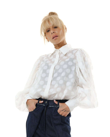Model wearing a white sheer polka dot shirt with puff sleeves, showcasing a stylish and sophisticated look.