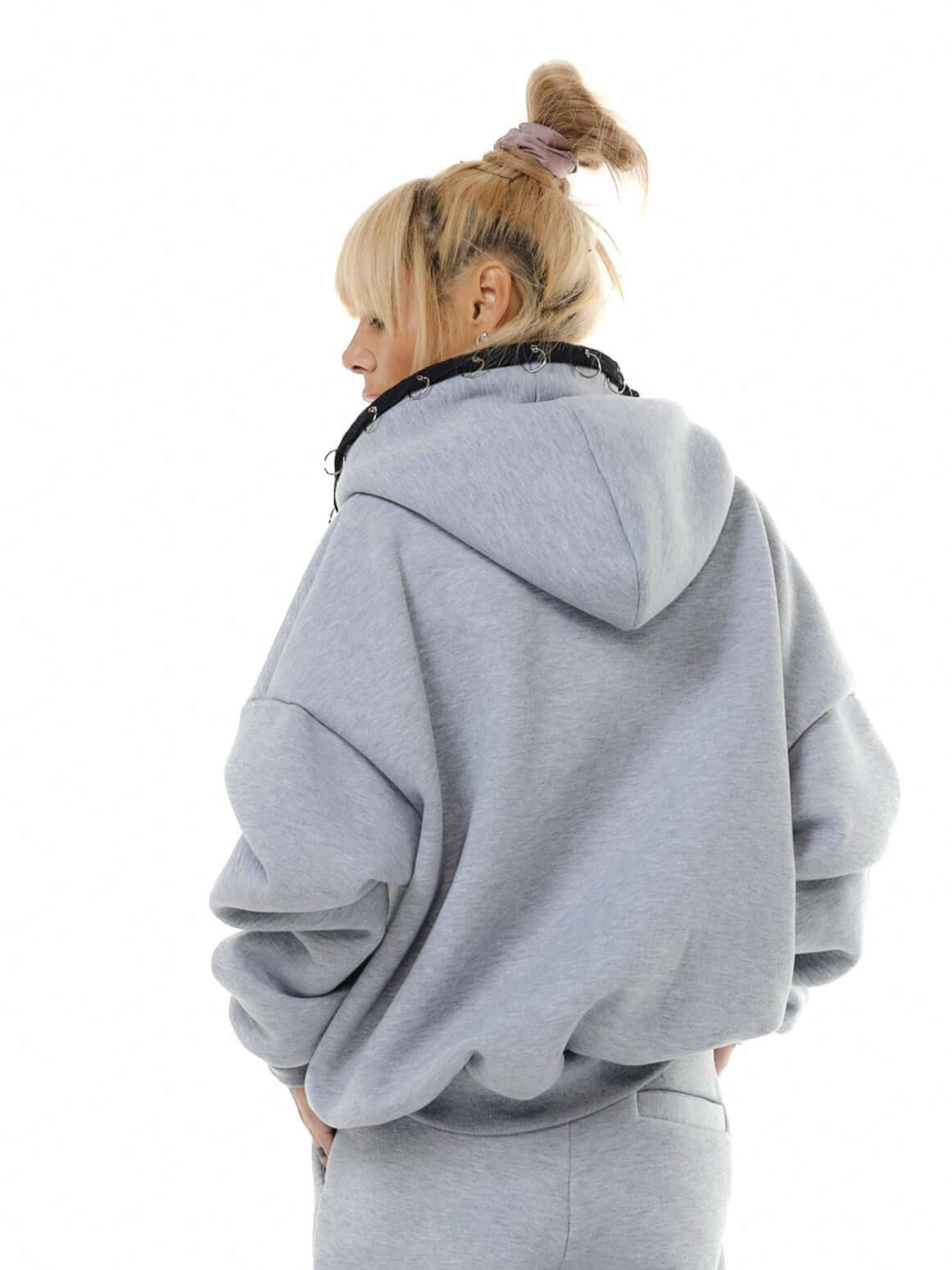 Back view of a model in a grey zip hoodie with oversized fit and drawstring, showcasing cozy streetwear style.