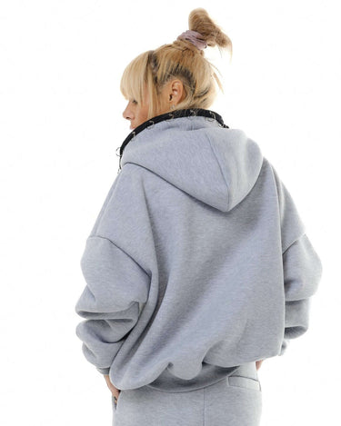 Back view of a model in a grey zip hoodie with oversized fit and drawstring, showcasing cozy streetwear style.