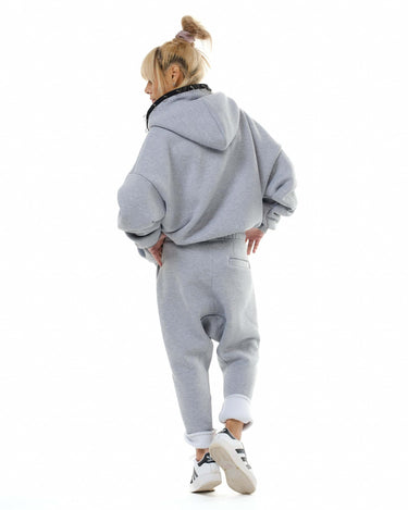 Fashionable model wearing a grey zip hoodie and jogger set, showcasing a relaxed-fit style from the back.