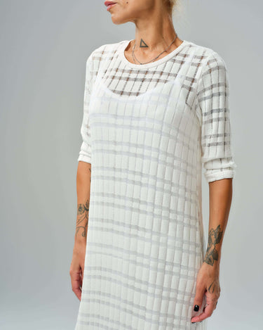 White knitted cotton dress featuring a semi-sheer texture and asymmetrical layered cut for elegant styling.