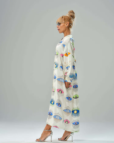 Woman in eye print shirt dress showcasing vibrant colors and a loose, lightweight design from a side view.