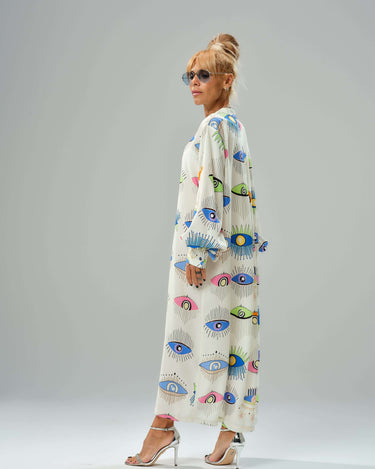 Woman wearing a vibrant eye print shirt dress, showcasing modern style with a loose fit and ¾ sleeves.