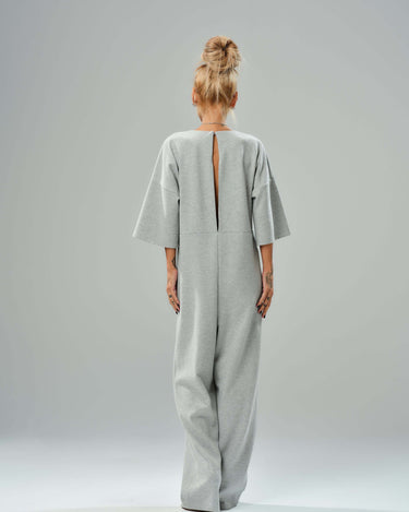 Grey wide-leg jumpsuit with open back, featuring cropped sleeves and relaxed fit, showcasing modern tailoring.