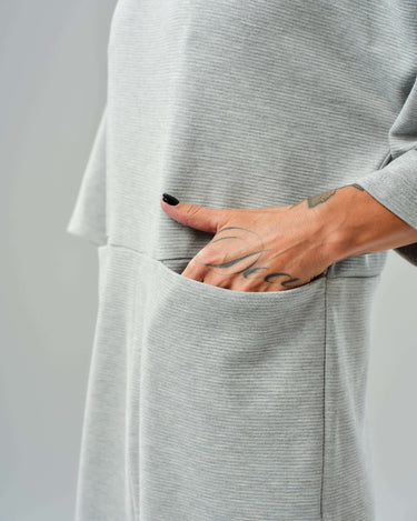 Detail of a grey wide-leg jumpsuit featuring a side pocket and relaxed fit with cropped sleeves.
