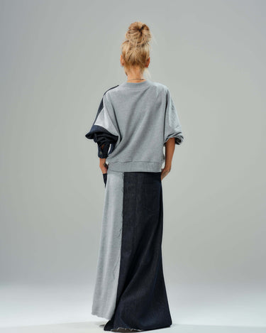 Back view of a grey and denim co-ord set featuring a relaxed sweatshirt and flowing maxi skirt with raw cut details.