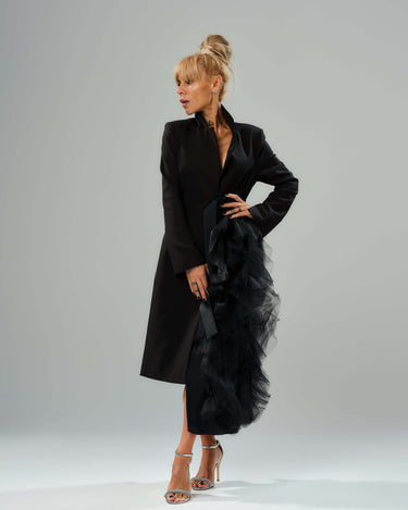 Elegant model showcasing a black tulle detail blazer with satin belt, dramatic tulle accent, and high collar.