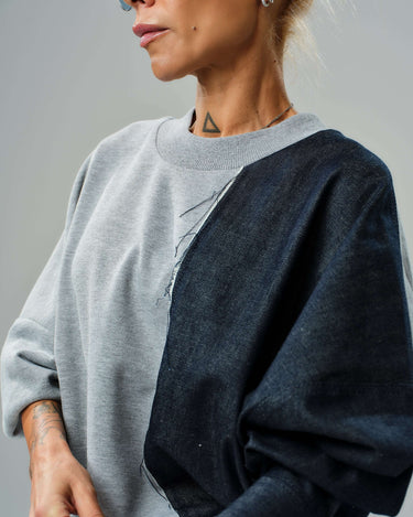 Model wearing a grey and denim co-ord set sweatshirt with raw cut details and asymmetric sleeve design.