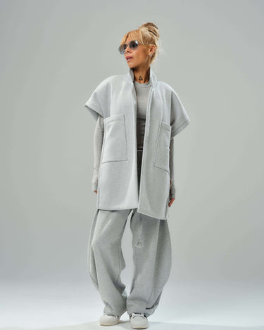 Model wearing oversized grey three-piece set with wide-leg trousers, ribbed top, and sleeveless vest.