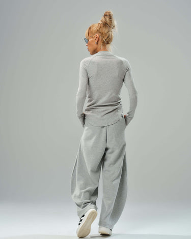 Model wearing a fitted long-sleeve gray top and oversized gray wide-leg trousers from the three-piece set.