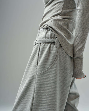Close-up of oversized grey three-piece set, featuring wide-leg drawstring trousers and fitted ribbed top in soft cotton blend.