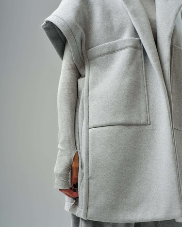 Oversized grey sleeveless vest with large pockets from a three-piece set on a model.