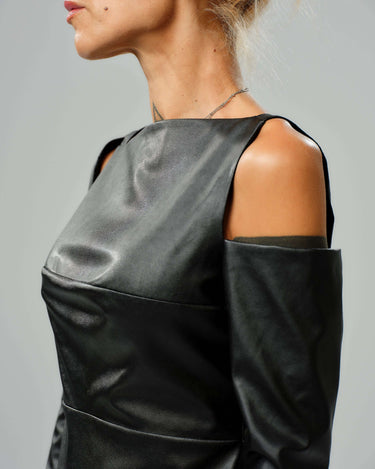 Close-up of a model wearing a black faux leather top with cut-out shoulder details, showcasing modern, edgy style.