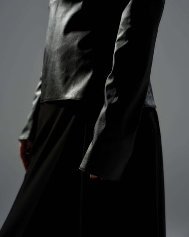 Close-up of a black faux leather top featuring a structured silhouette and cut-out shoulder details.