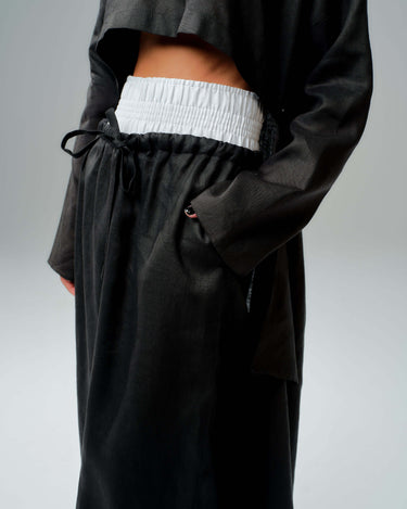 Close-up of black co-ord set featuring wide-leg pants with elasticated waistband and drawstring for adjustable fit.