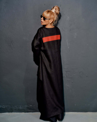 Model wearing a black co-ord set tunic with red stripe, showcasing a minimalist and modern fashion style.