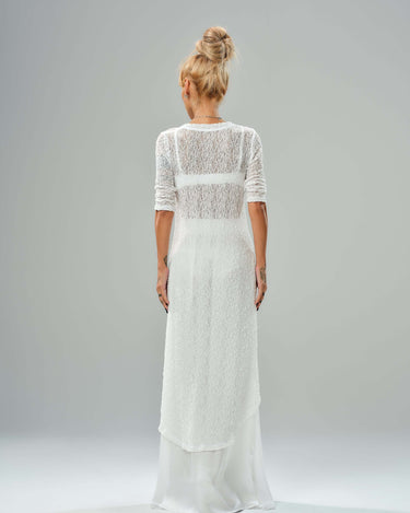 Back view of a woman in a white textured tunic and flowing maxi skirt, showcasing an elegant contemporary look.