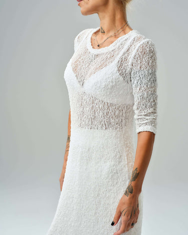 Profile view of a woman wearing a sheer white tunic from a maxi co-ord set, showcasing textured fabric.