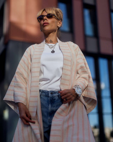 Woman wearing a striped linen-cotton kimono over a white top and denim, showcasing a relaxed and elegant style.