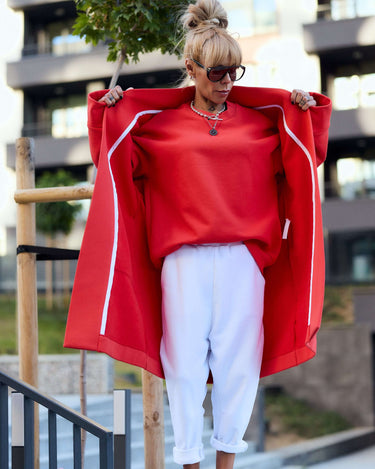 Stylish woman in a red oversized coat and white pants, showcasing a relaxed, bold outfit perfect for casual styling.