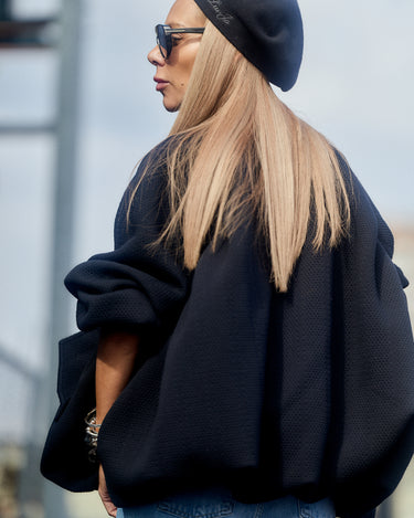 A stylish woman wearing a Black Oversized Textured Jacket with a black beret and sunglasses.