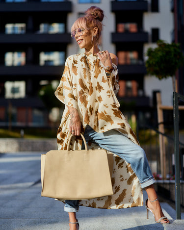 Beige Printed Asymmetric Tunic styled off the shoulder with jeans and a beige handbag in a chic urban setting.