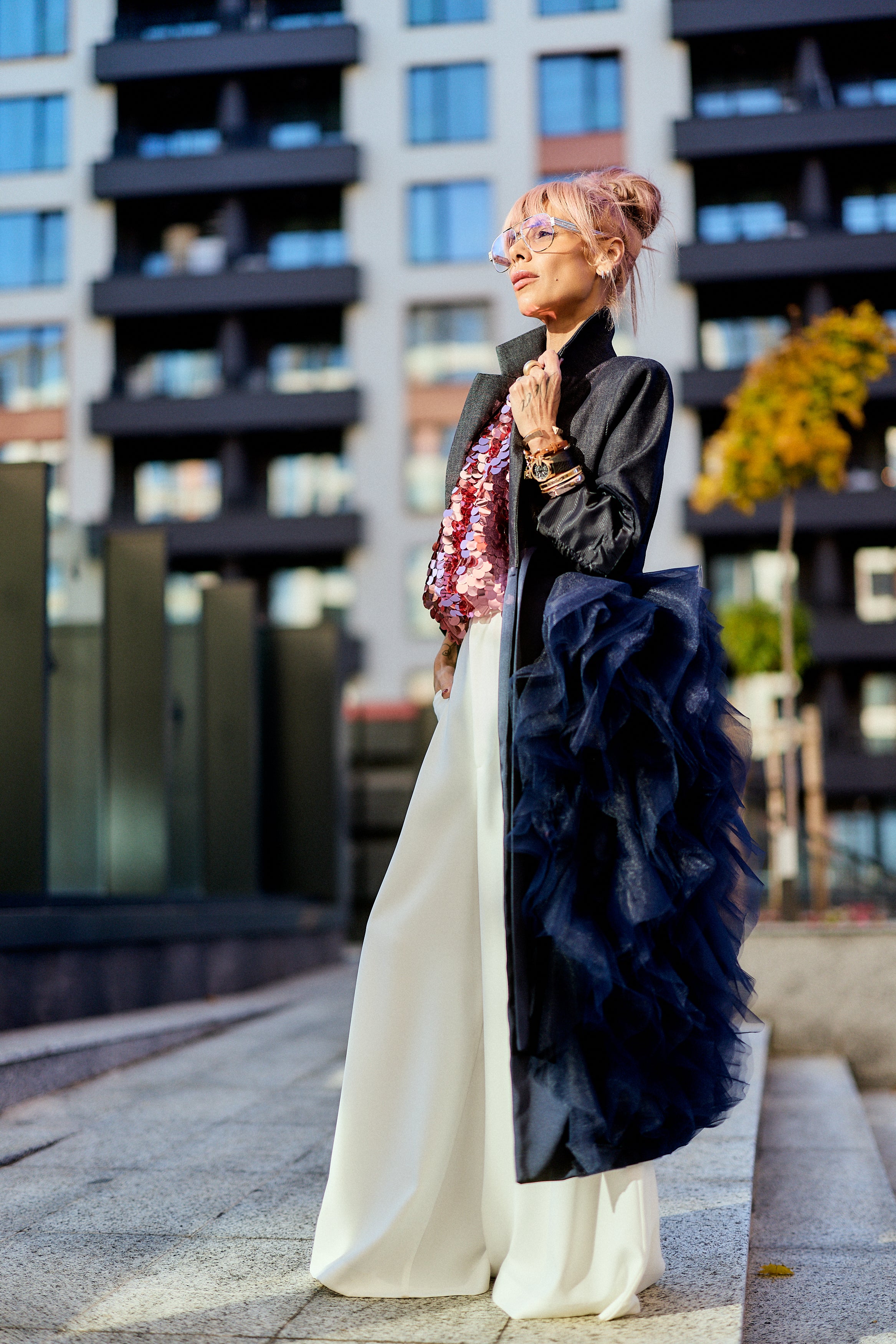 Model showcasing the Denim Tulle Detail Blazer with tulle ruffle, styled with wide-leg pants in an urban setting.