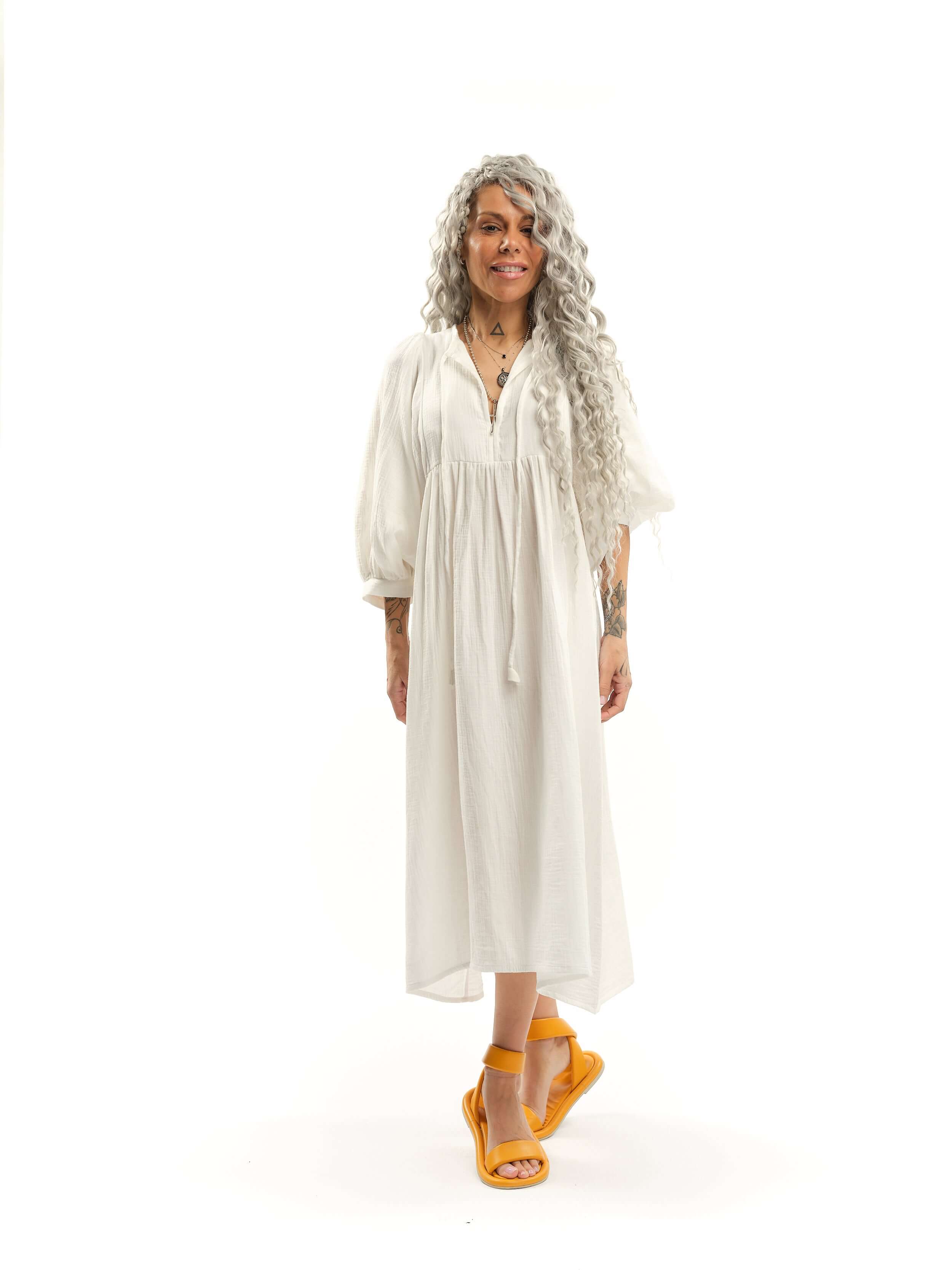 Cotton-Blend Midi Dress Designed with a relaxed, babydoll silhouette, this dress drapes effortlessly, letting the fabric move with ease. The billowing sleeves fall just above the wrists, adding a touch of structure to the fluid shape, while the v-neckline