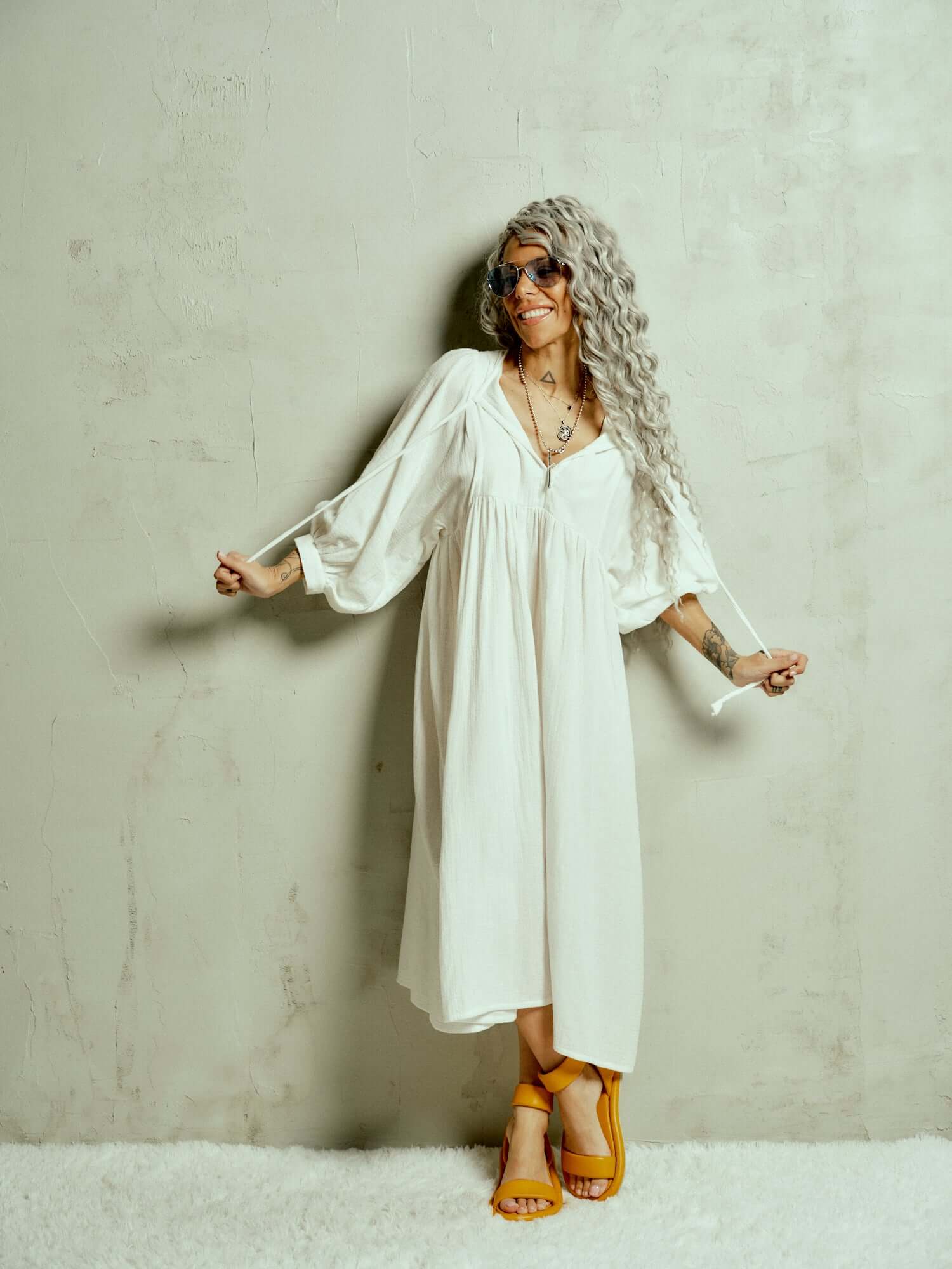 Cotton-Blend Midi Dress Designed with a relaxed, babydoll silhouette, this dress drapes effortlessly, letting the fabric move with ease. The billowing sleeves fall just above the wrists, adding a touch of structure to the fluid shape, while the v-neckline