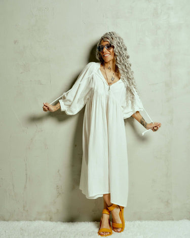 Cotton-Blend Midi Dress Designed with a relaxed, babydoll silhouette, this dress drapes effortlessly, letting the fabric move with ease. The billowing sleeves fall just above the wrists, adding a touch of structure to the fluid shape, while the v-neckline