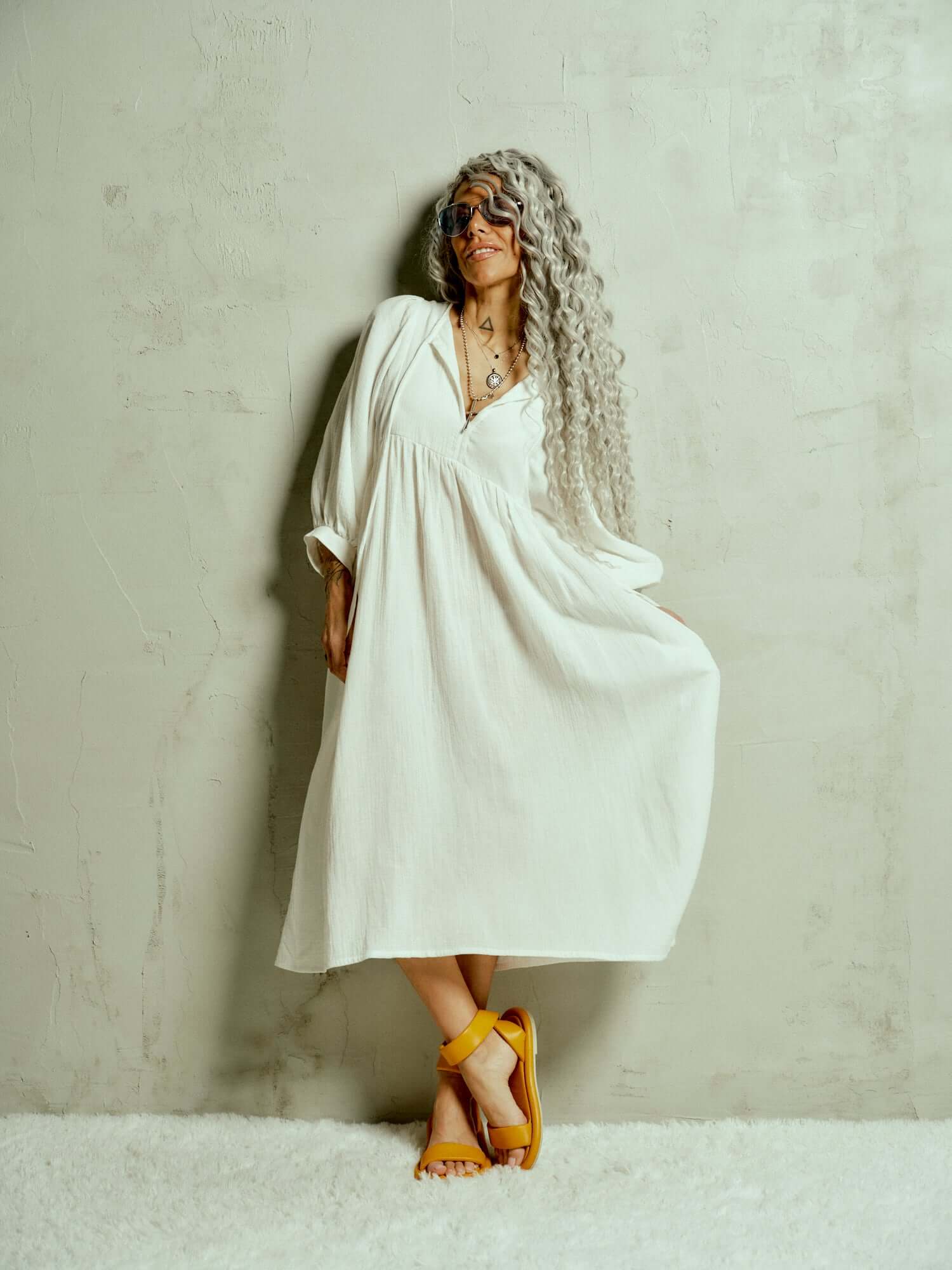 Cotton-Blend Midi Dress Designed with a relaxed, babydoll silhouette, this dress drapes effortlessly, letting the fabric move with ease. The billowing sleeves fall just above the wrists, adding a touch of structure to the fluid shape, while the v-neckline