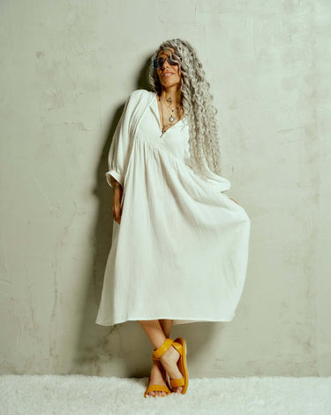 Cotton-Blend Midi Dress Designed with a relaxed, babydoll silhouette, this dress drapes effortlessly, letting the fabric move with ease. The billowing sleeves fall just above the wrists, adding a touch of structure to the fluid shape, while the v-neckline