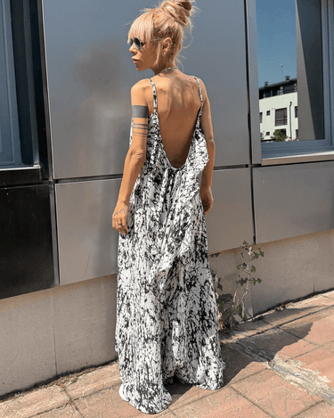 Model wearing an Ink Veil White Maxi Dress with an open back and black-and-white ink-splatter print against an urban backdrop.