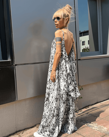Model wearing black-and-white Ink Veil Maxi Dress with open back and ruffles, showcasing fluid silhouette and bold design.