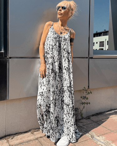 Model wearing the Ink Veil White Maxi Dress with black-and-white ink-splatter print and sunglasses.