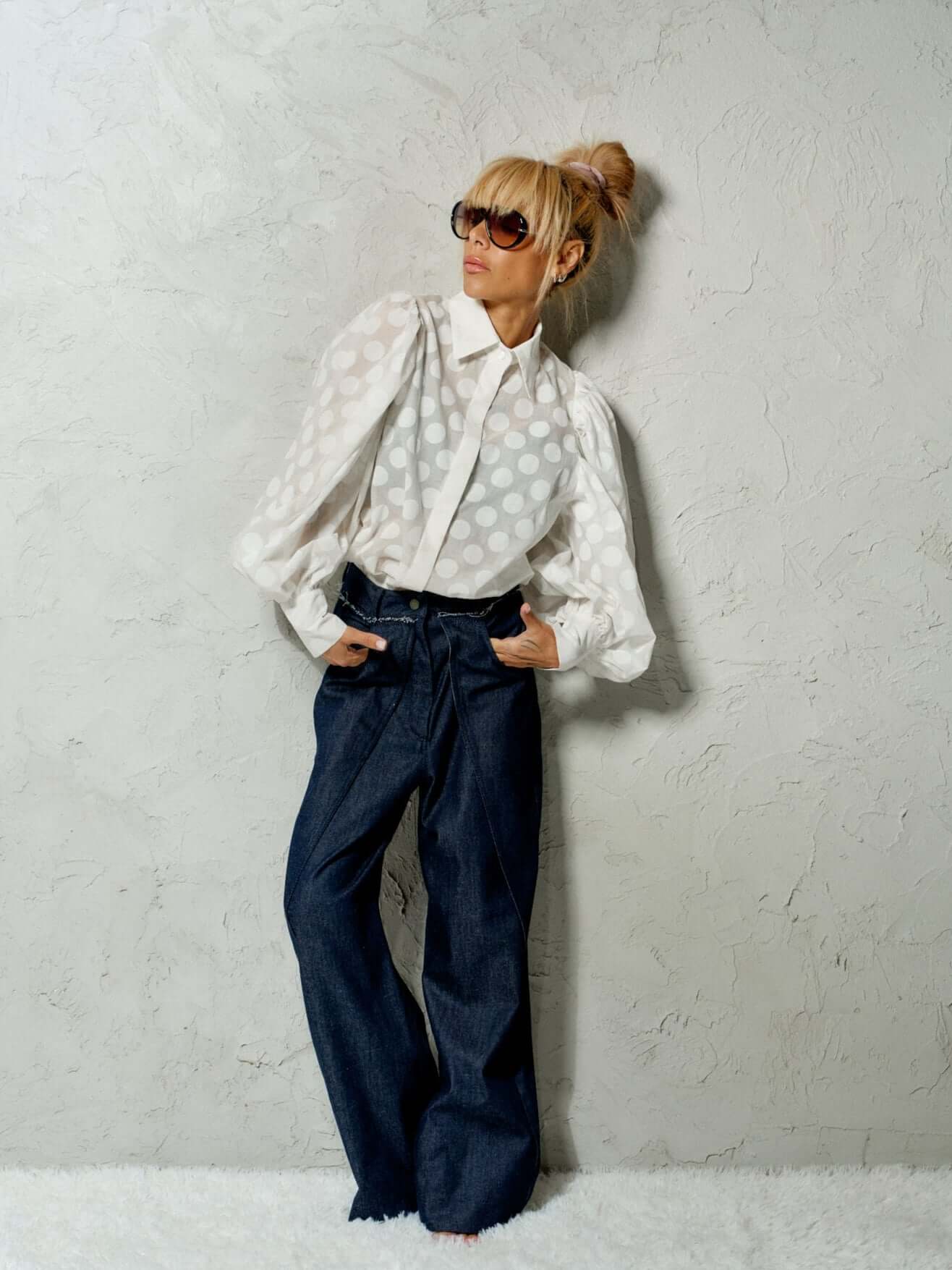 Stylish model wearing a white sheer polka dot puff sleeve shirt with denim pants, showcasing a modern look.