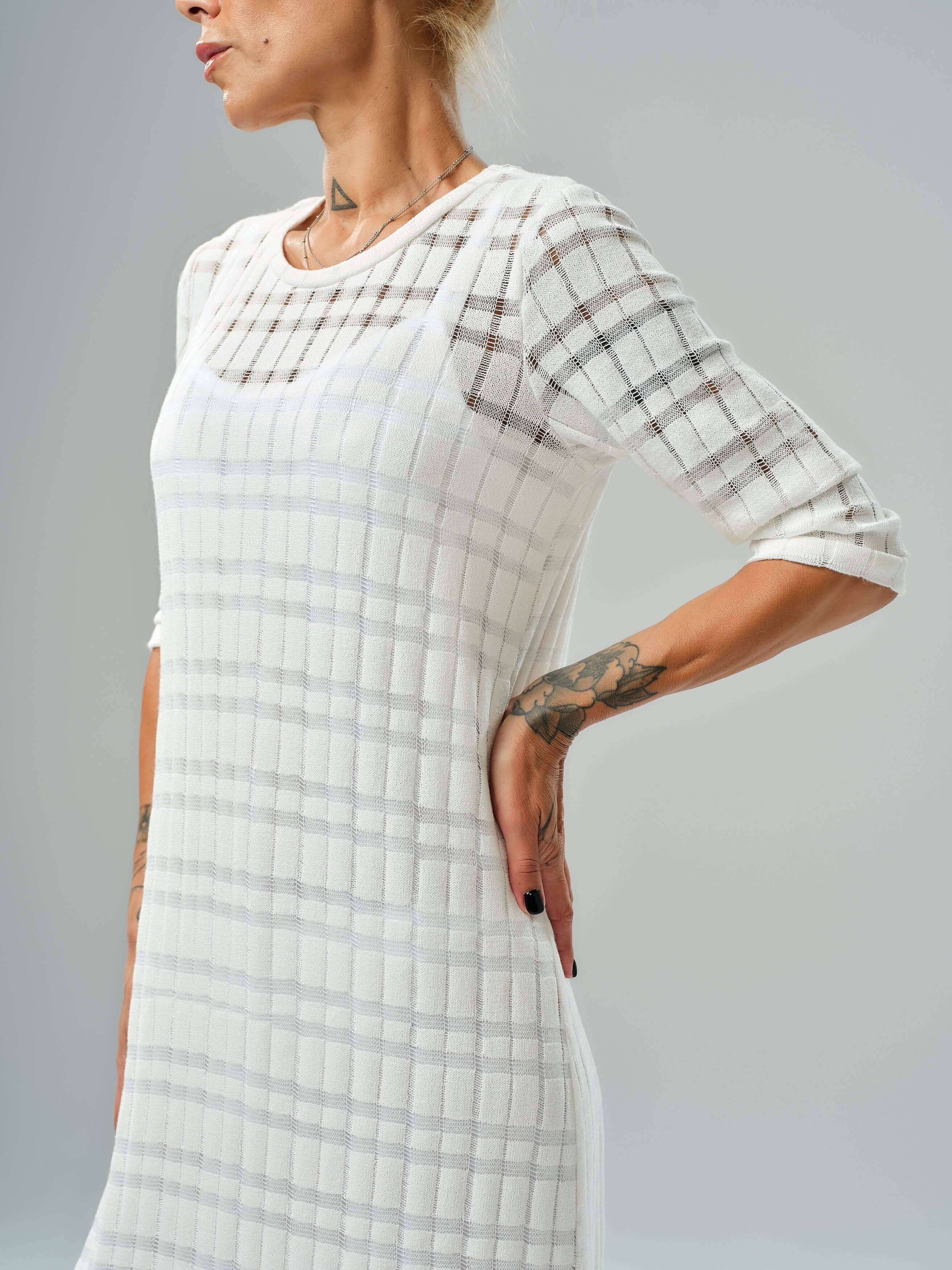 White knitted cotton dress with asymmetrical cut and semi-sheer texture, perfect for casual and evening wear.