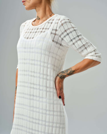 White knitted cotton dress with asymmetrical cut and semi-sheer texture, perfect for casual and evening wear.