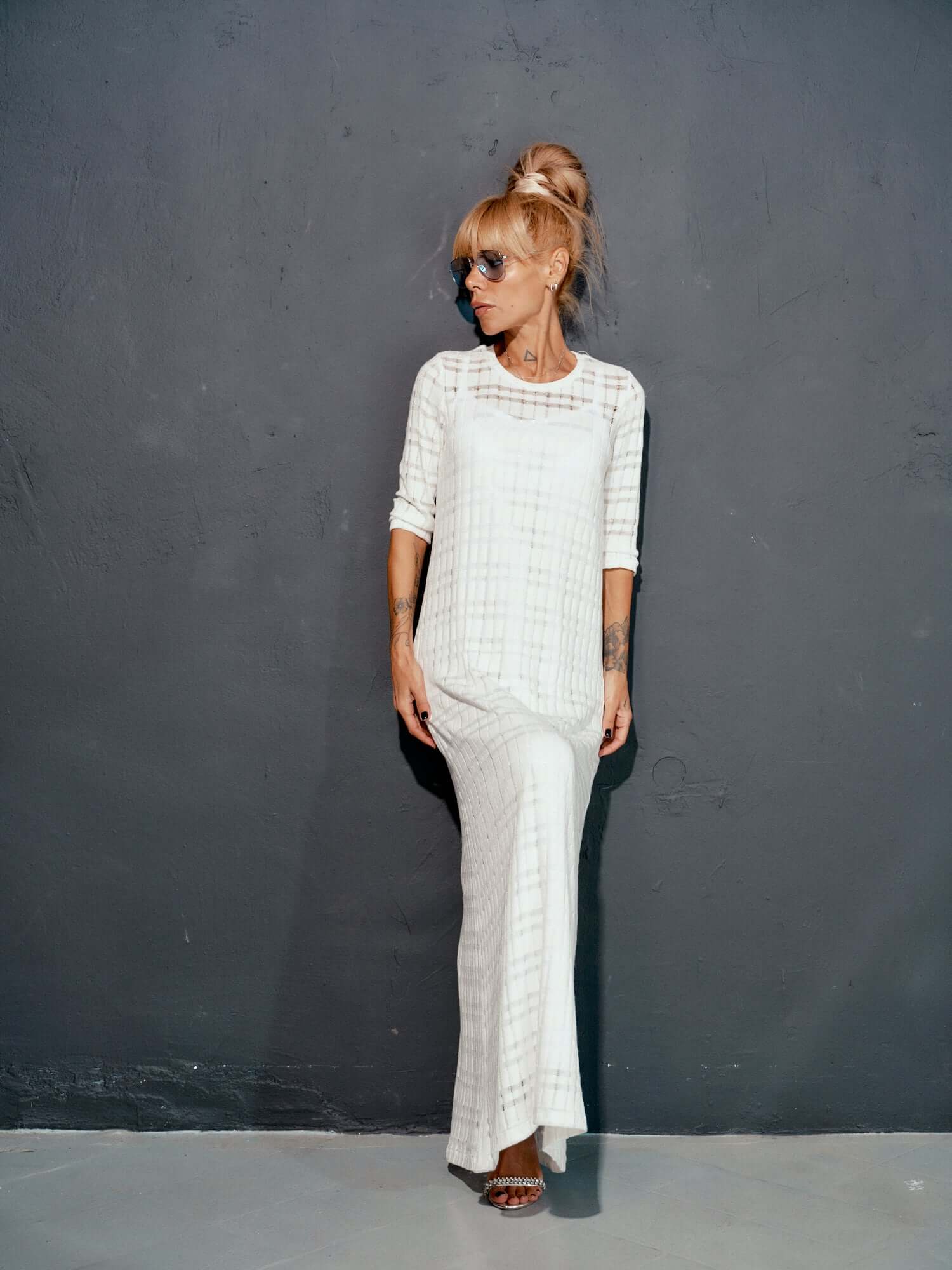 Model wearing a white knitted cotton dress with a sleek design against a dark background.