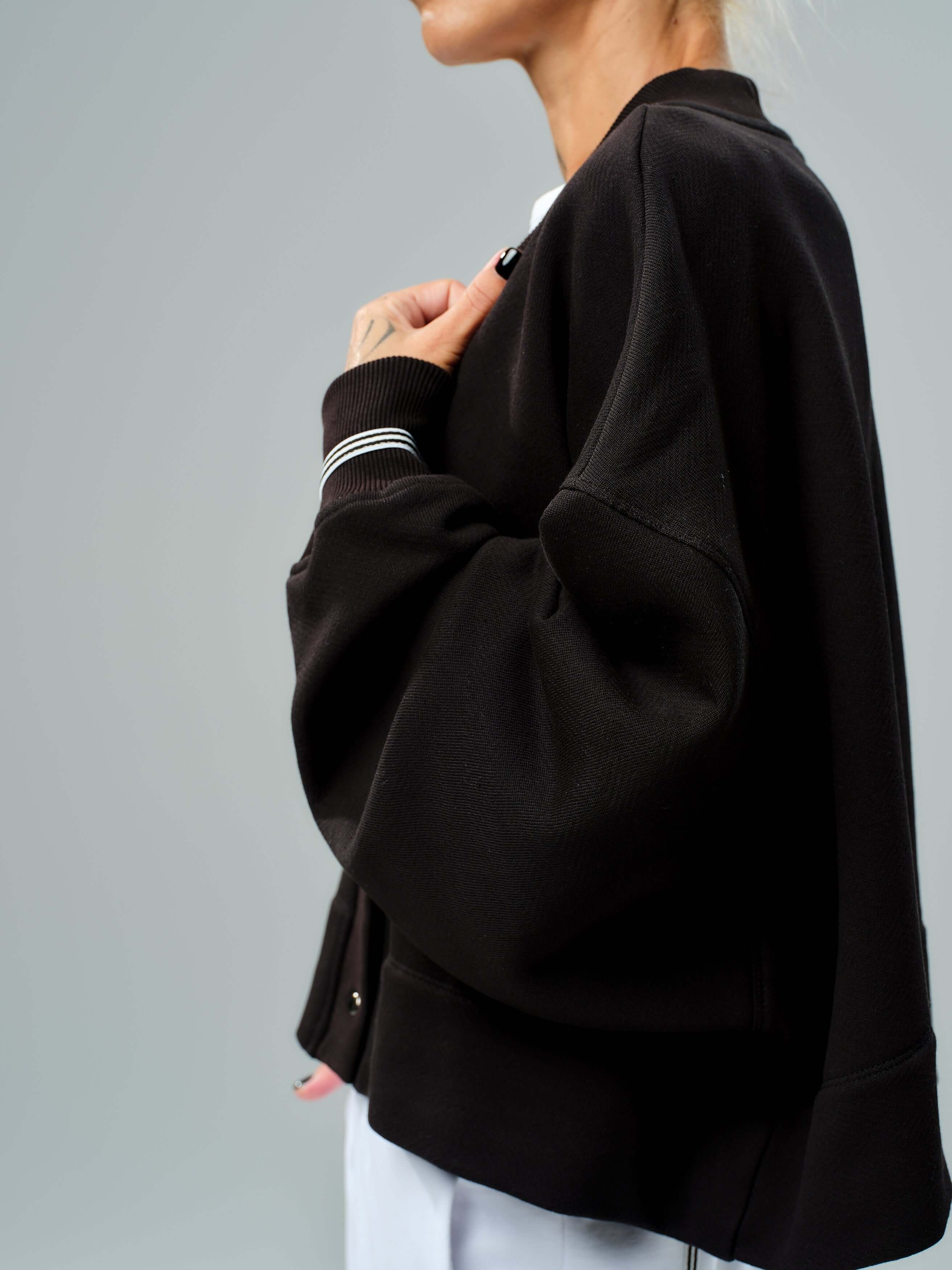 Black snap-button jacket with relaxed silhouette, dropped shoulders, and ribbed cuffs for casual style.