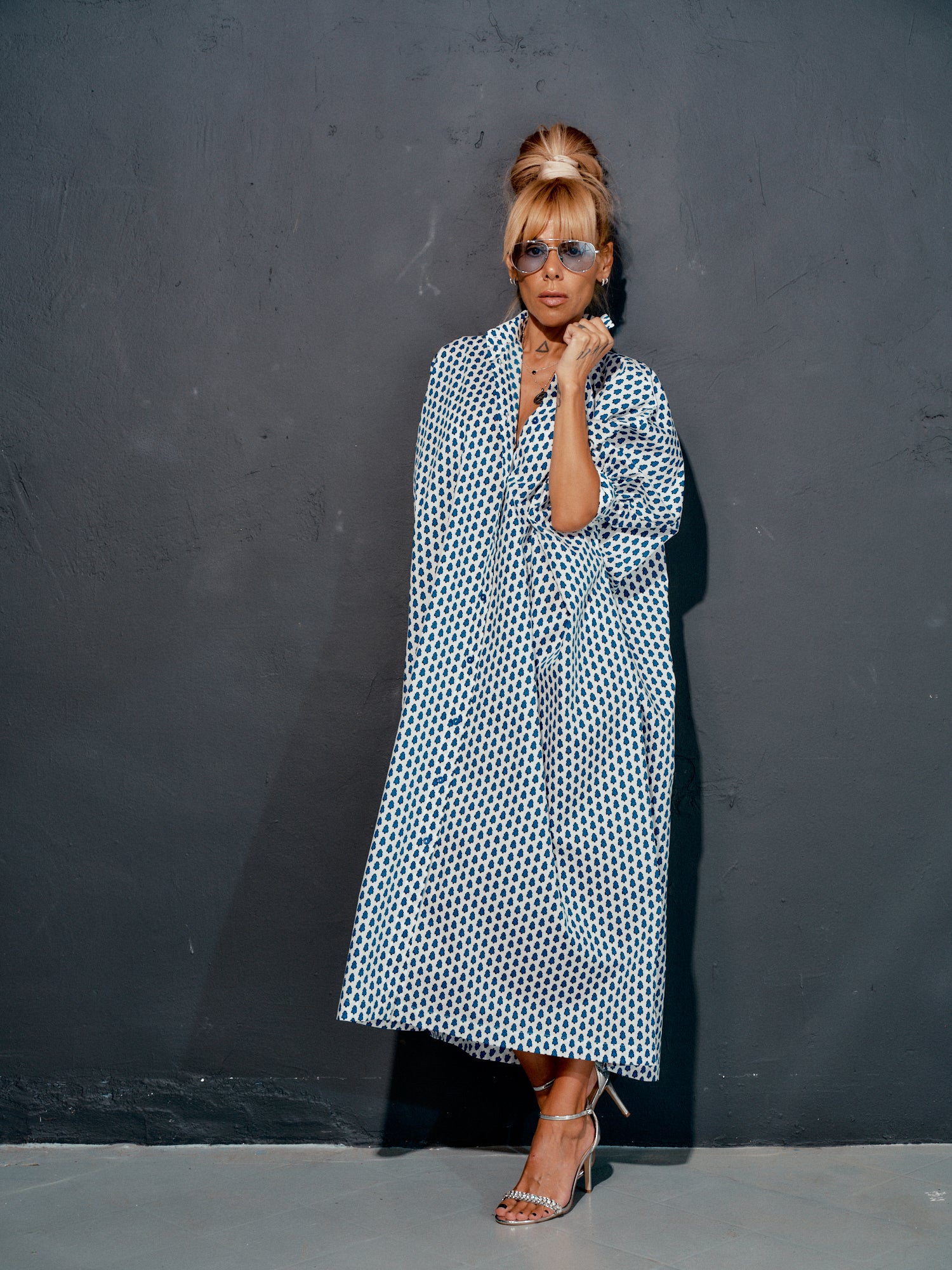 Woman in an oversized shirt dress with blue micro floral print, styled elegantly against a grey background.