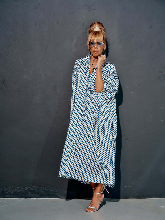 Woman in an oversized shirt dress with blue micro floral print, styled elegantly against a grey background.