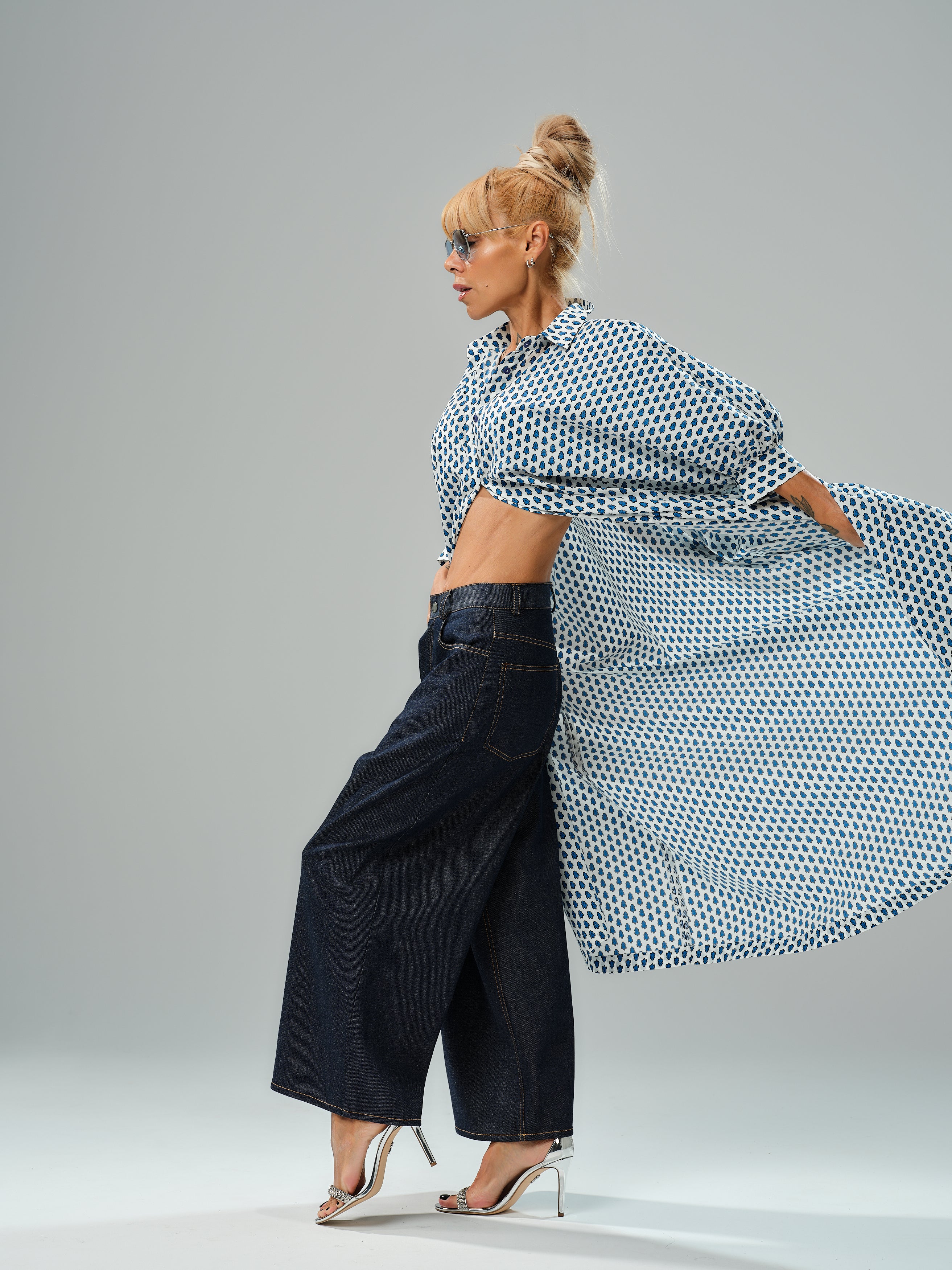 Model showcasing an oversized shirt dress with a blue micro floral print, styled with wide-leg jeans and heeled sandals.