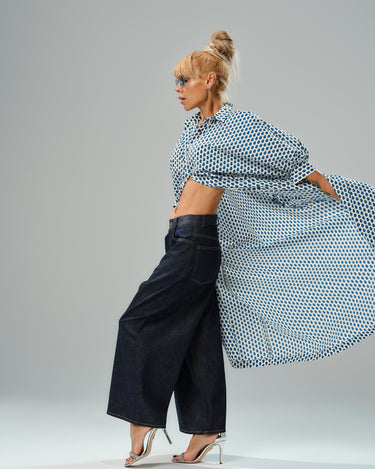 Model showcasing an oversized shirt dress with a blue micro floral print, styled with wide-leg jeans and heeled sandals.
