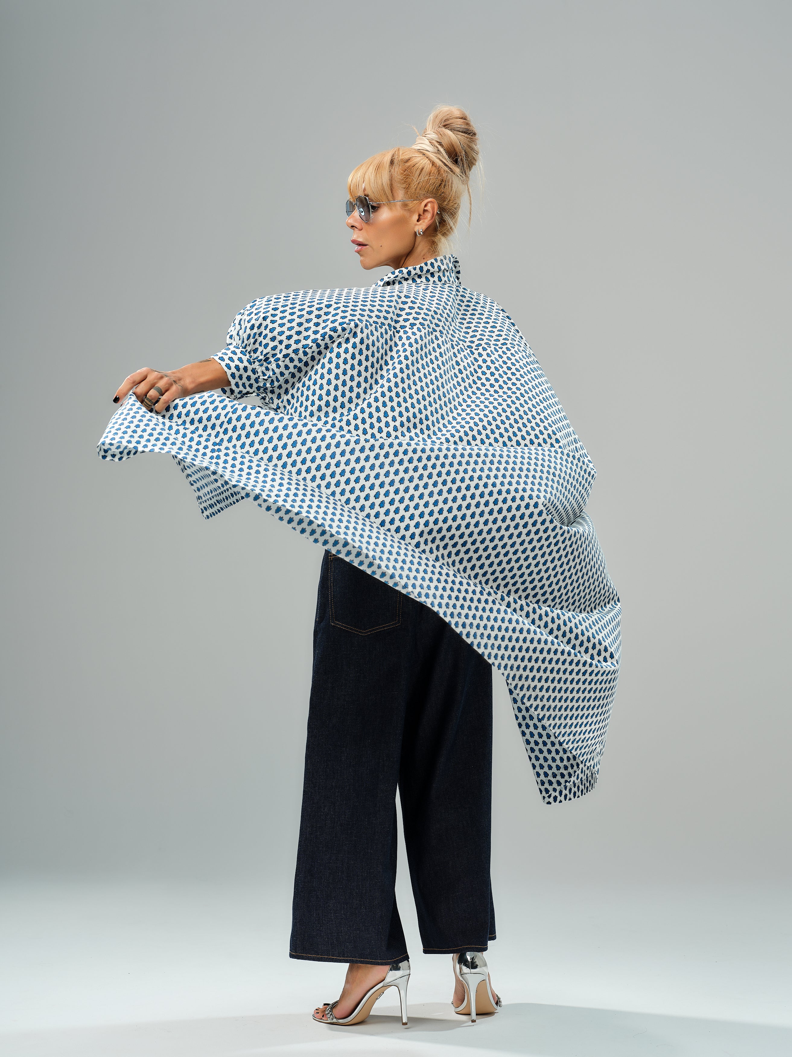 Model wearing an oversized shirt dress with blue micro floral print, styled with wide-leg jeans and stylish heels.