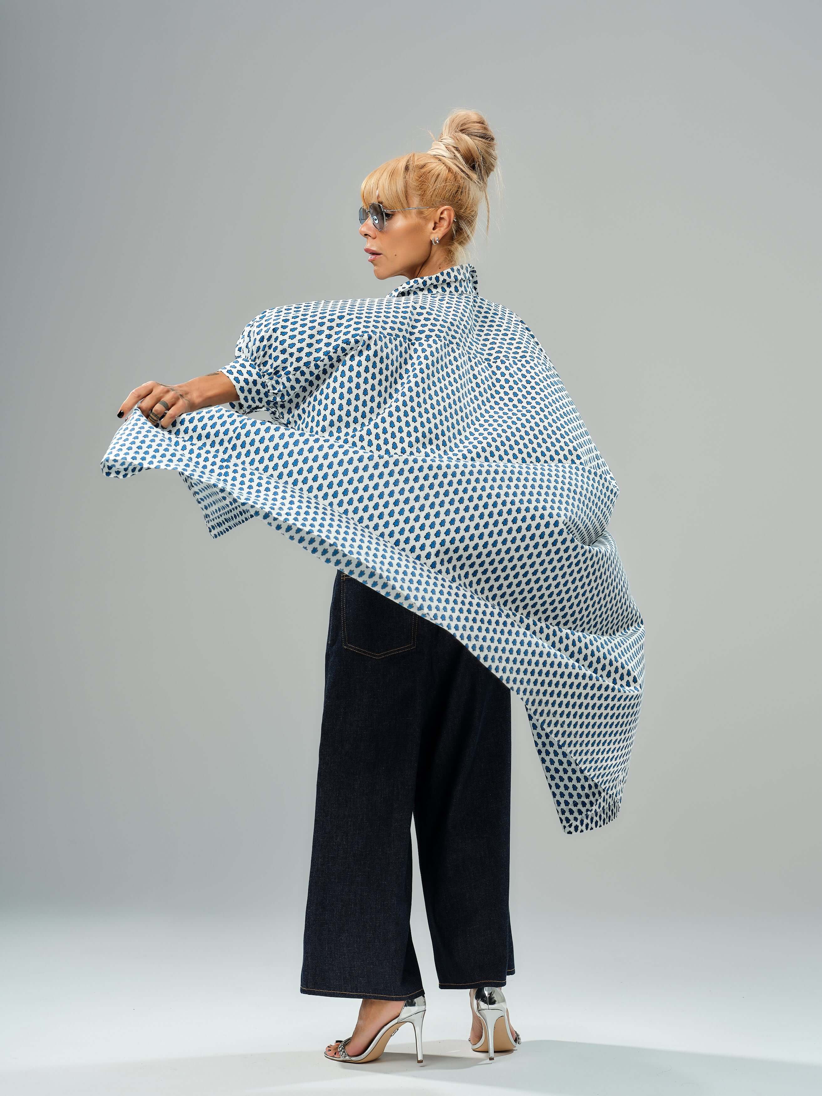 Model wearing an oversized shirt dress with blue micro floral print, styled with wide-leg jeans and stylish heels.
