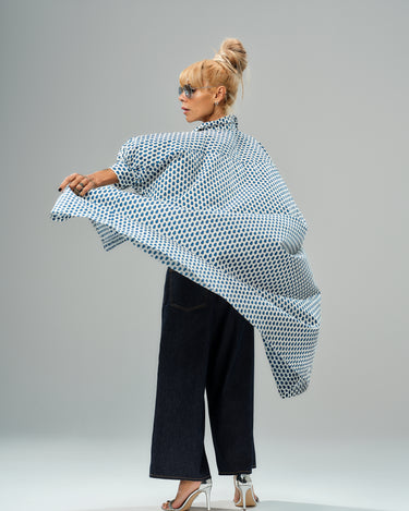 Model wearing an oversized shirt dress with blue micro floral print, styled with wide-leg jeans and stylish heels.