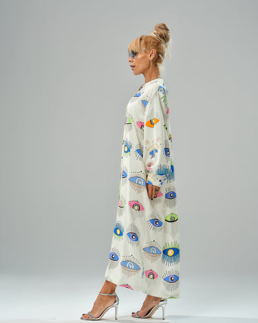 Woman in eye print shirt dress showcasing vibrant colors and a loose, lightweight design from a side view.