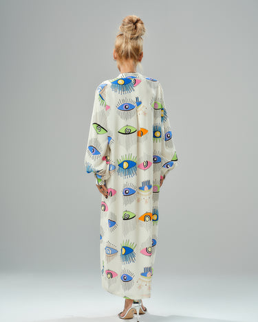 Back view of a woman in a vibrant eye print shirt dress, featuring ¾ sleeves and a loose, lightweight design.
